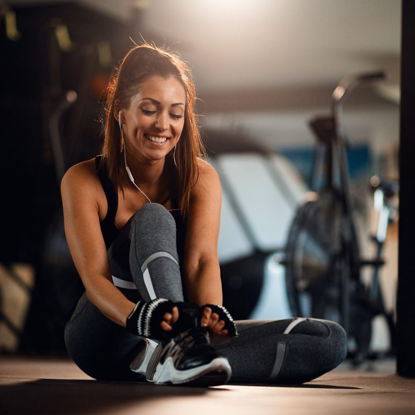 young-happy-sportswoman-getting-ready-workout-tying-shoelace-fitness-center_Easy-Resize.com